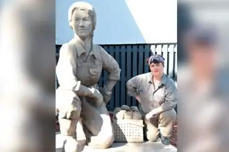 PAYING HOMAGE: Sharon Vassalo playing Bobby with a statue at the Birkdale Hall commemorating the work of the local Land Army. PHOTO: GREG POPE