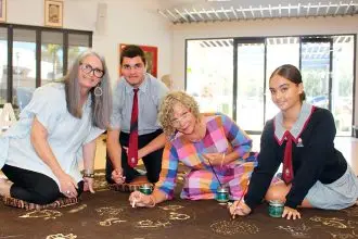COLLABORATION: Artist Tania Budd and Sonja Carmichael add their drawings to the story cloth alongside Carmel College students. Photo: Jordan Crick
