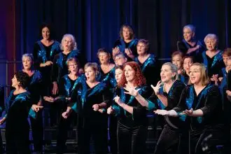 Megan Bishop (chair of the regional convention), Brooke Ovenden and Kate Becroft perform alongside their Chorus.