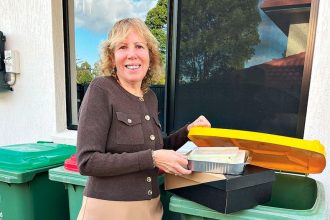 LEADING THE WAY: Cr Tracey Huges placing the correct recyclables into a yellow bin.